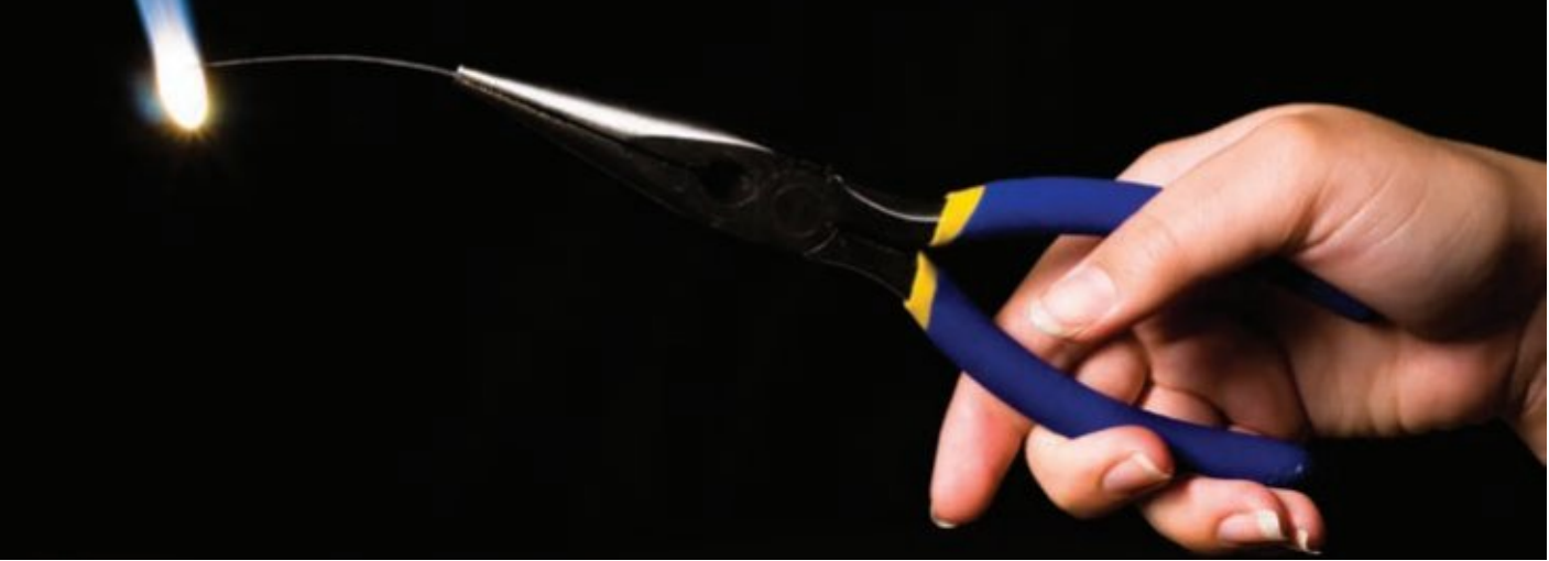 A hand holding a pair of blue-handled needle-nose pliers is against a black background. The pliers grip a thin metal wire, glowing orange at one end, showing it's heated.